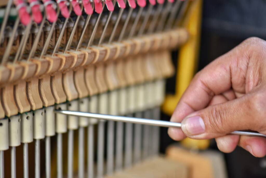 Man’s hand regulating the action on a piano so the musician playing can be amazingly expressive