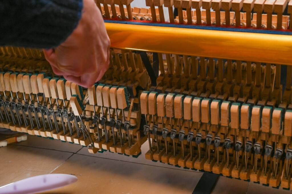 The tuner is in the process of repairing and tuning the piano